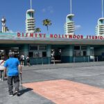 Entrada principal de Disney's Hollywood Studios en Walt Disney World, Orlando, con su edificio turquesa, letras rojas y visitantes bajo un cielo azul