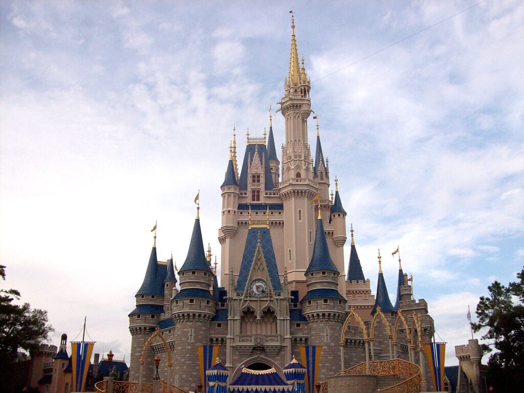 Castillo de Cenicienta del Magic Kingdom con torres azules y doradas bajo un cielo con nubes