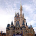 Castillo de Cenicienta del Magic Kingdom con torres azules y doradas bajo un cielo con nubes