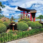 Puerta torii roja junto a la laguna en el pabellón de Japón de EPCOT, con bonsáis en primer plano