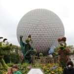 EPCOT Flower & Garden Festival: topiarios verdes de personajes de Disney junto a flores de colores frente a la esfera plateada de Spaceship Earth, con visitantes