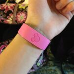 My Disney Experience: pulsera MagicBand rosada con el logo de Mickey en relieve, puesta en la muñeca de una persona