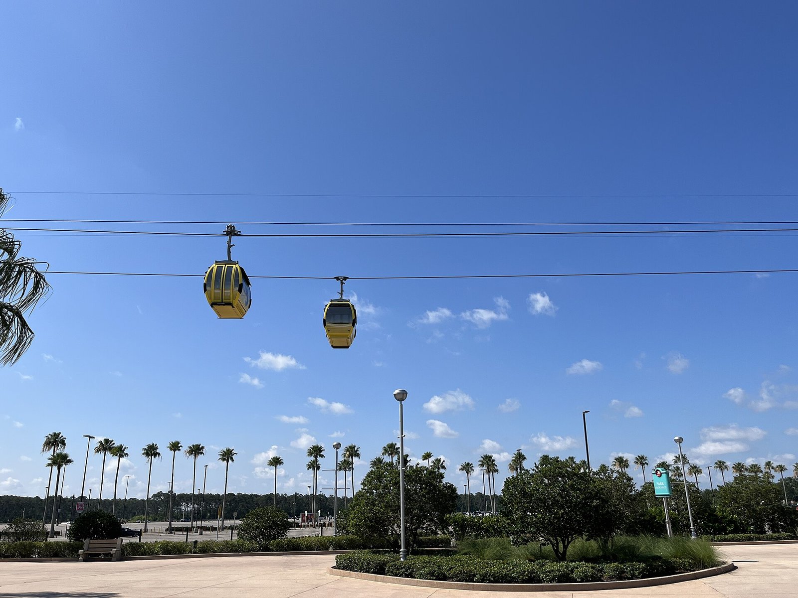 Dos góndolas amarillas del Disney Skyliner sobre una línea de palmeras, con cielo azul, en Walt Disney World, Orlando