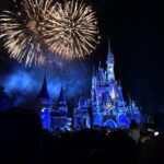 Shows nocturnos de Disney: fuegos artificiales dorados sobre el castillo de Cenicienta iluminado de azul, con siluetas del público en primer plano