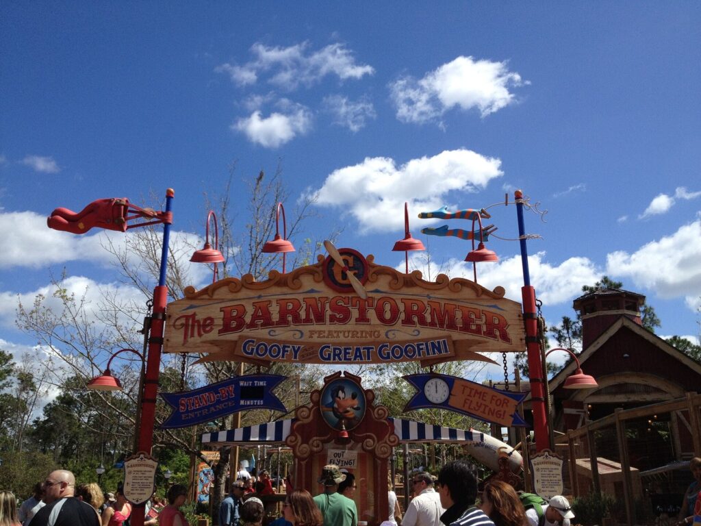 Entrada de la atracción infantil The Barnstormer en Storybook Circus, Magic Kingdom, con familias y cielo azul