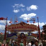 Entrada de la atracción infantil The Barnstormer en Storybook Circus, Magic Kingdom, con familias y cielo azul